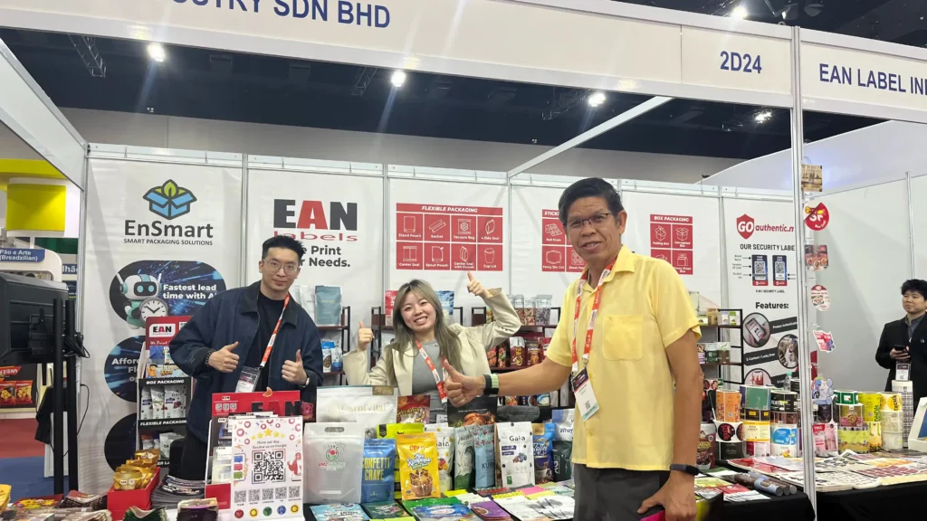 EAN Label team and visitor at the MIHAS 2026 booth featuring flexible packaging, labels and custom packaging samples
